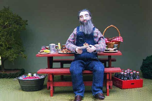 This Miniature Doll sits at a park bench in his overalls.